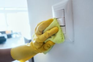 person cleaning and disinfecting electric switches